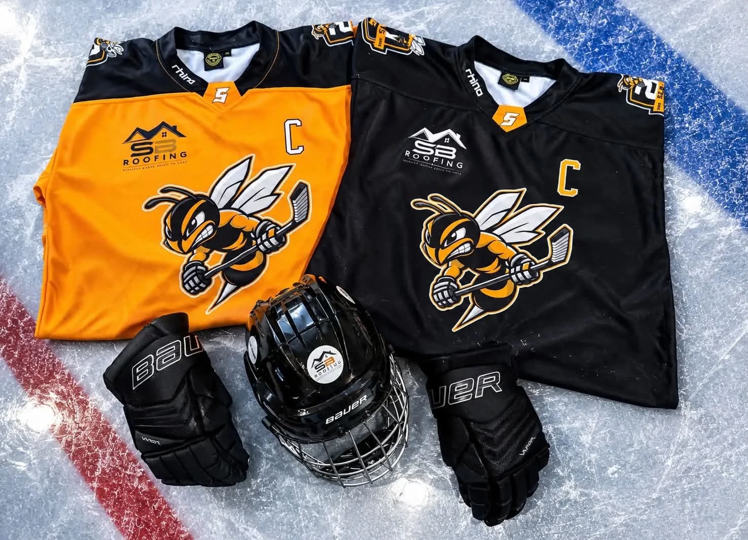 Sutton Sting U16 home and away shirts with the SB Roofing logo, laid on the ice with gloves and a helmet